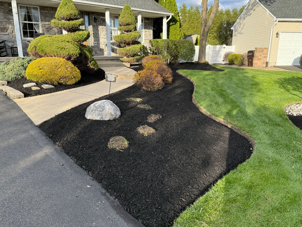 Well-manicured front yard with landscaped bushes, mulch, and stone accents.